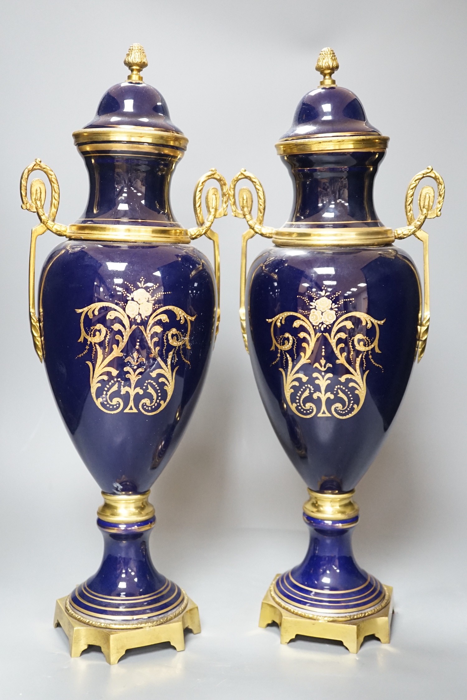 A pair of Sevres style urns and covers, with gilt metal mounts, 50 cms high